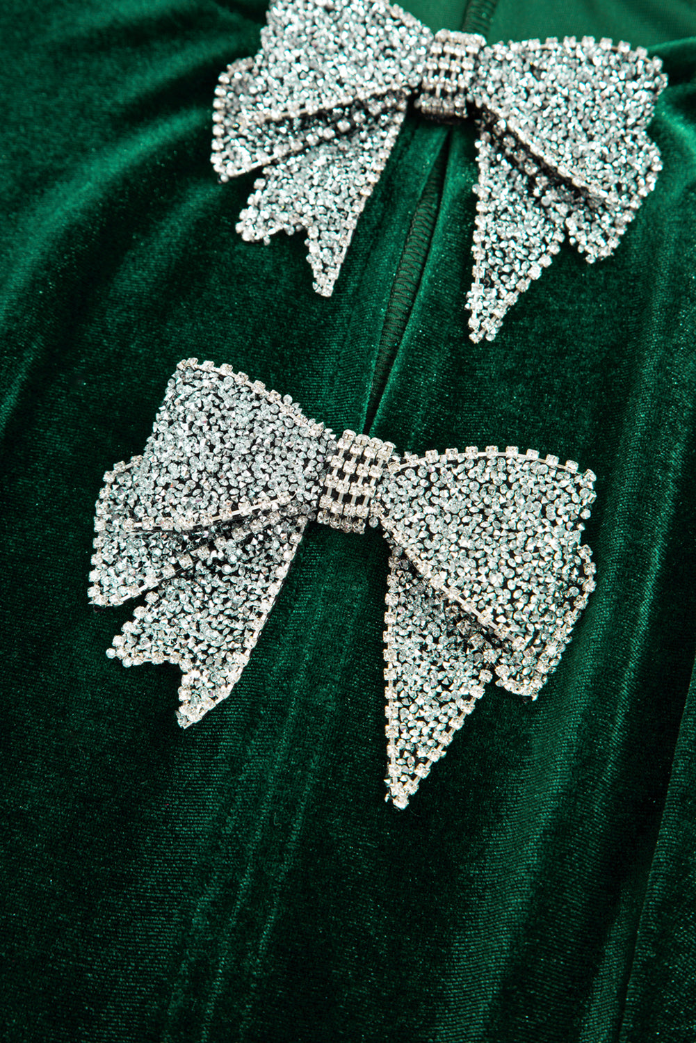 Close-up of sparkling rhinestone bows on dark green velvet fabric