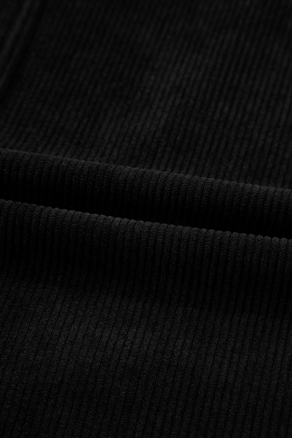 Close-up of black ribbed corduroy fabric texture, soft textile material