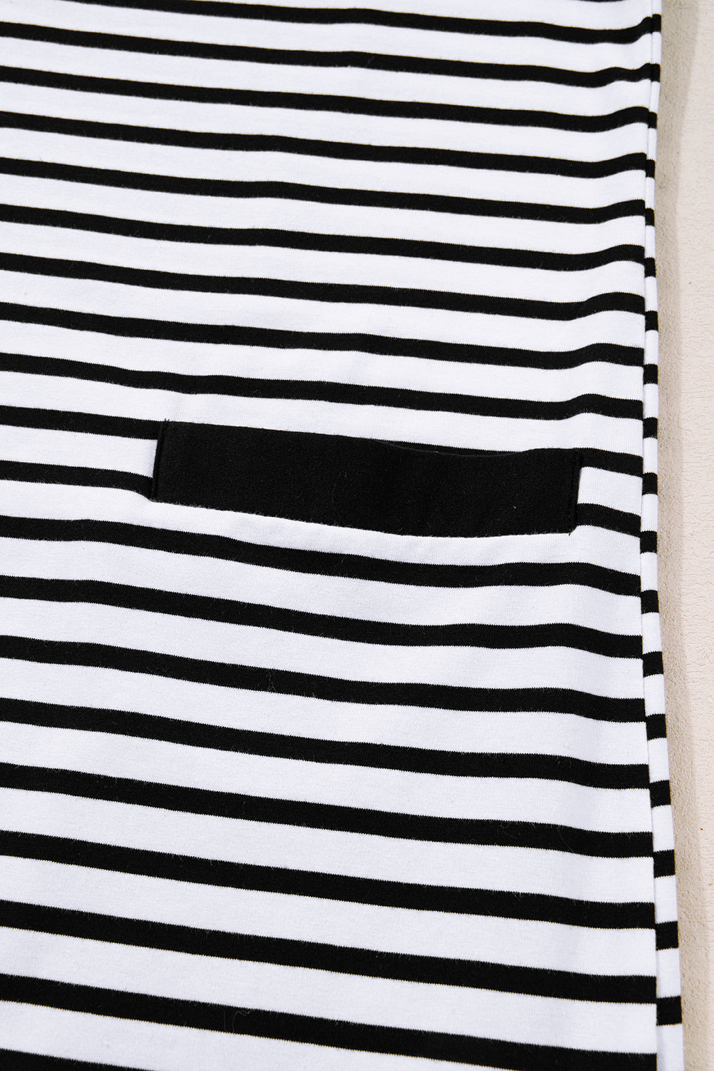 Black and white striped fabric with a black pocket detail, close-up view