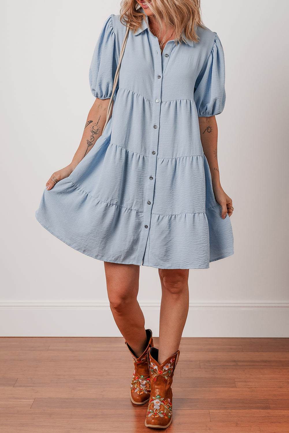 Woman in light blue button-down short dress with puff sleeves and floral cowboy boots