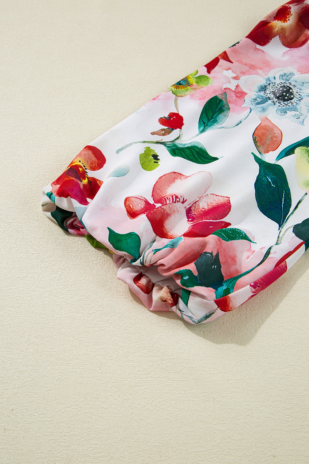 Colorful floral long sleeve blouse with gathered cuffs on a neutral background
