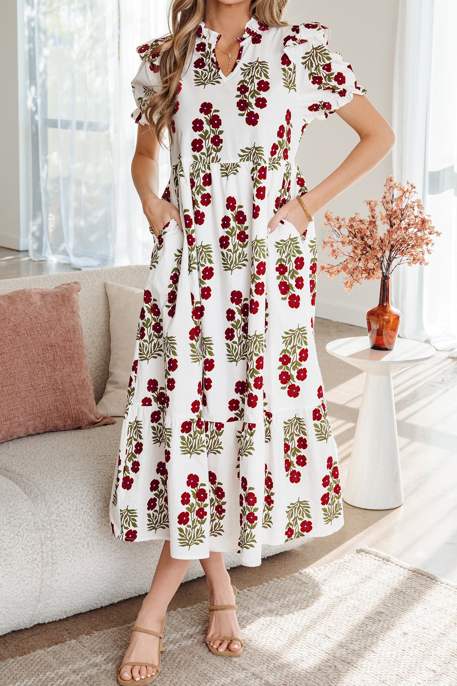 Woman wearing a white floral midi dress with red flowers and green leaves, ruffle sleeves
