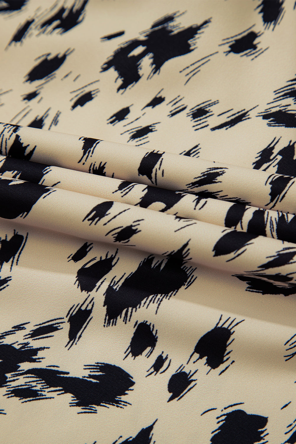 Beige fabric with black abstract animal print pattern, close-up textile texture