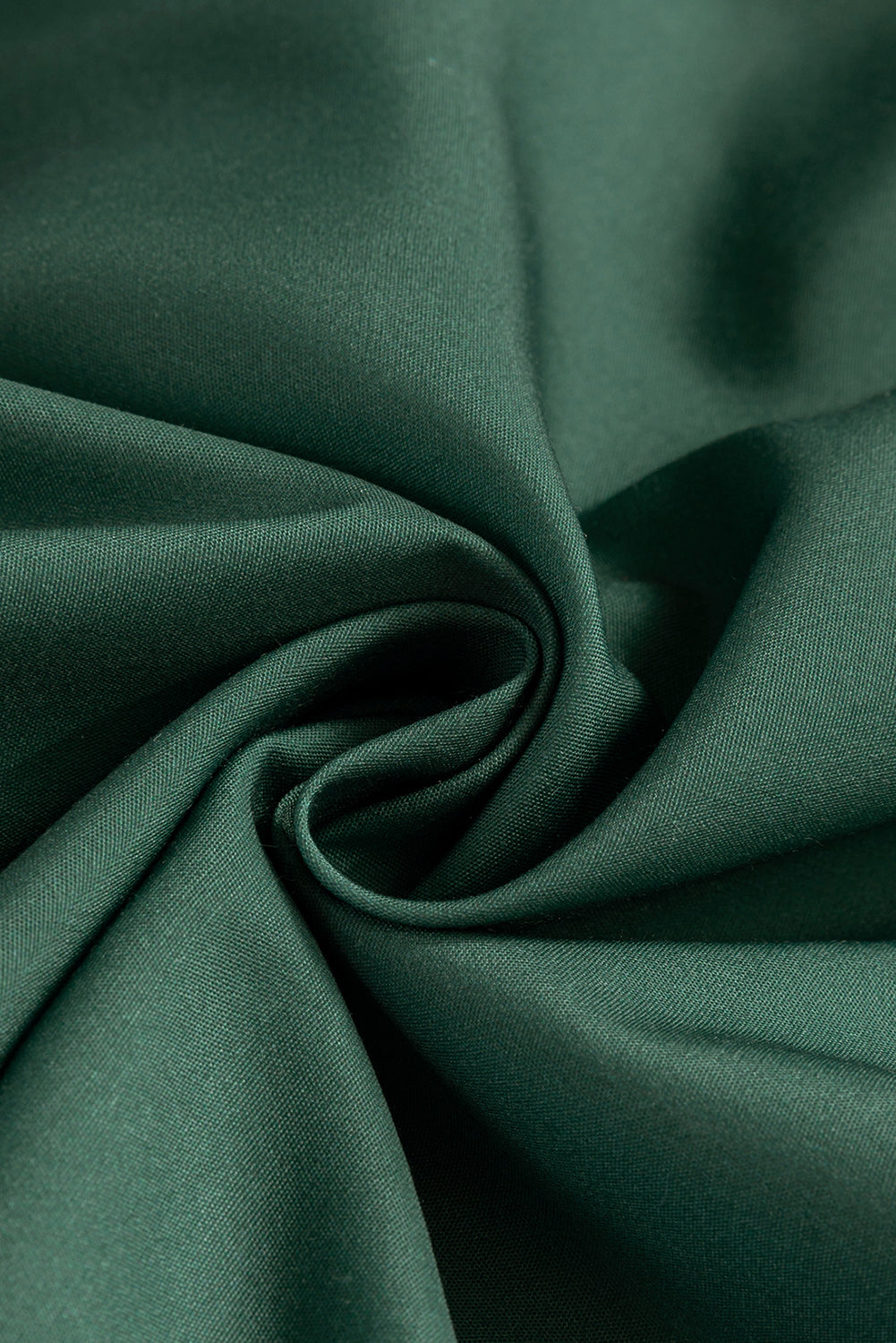 Close-up of smooth dark green fabric with soft folds, textile texture detail