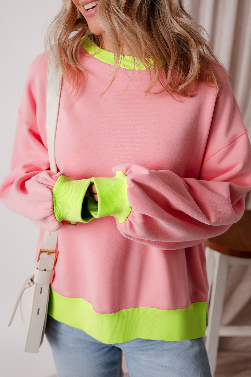 Розов дамски суитшърт с неоново зелени маншети, яка и кант, носен с бежова презрамка и дънки