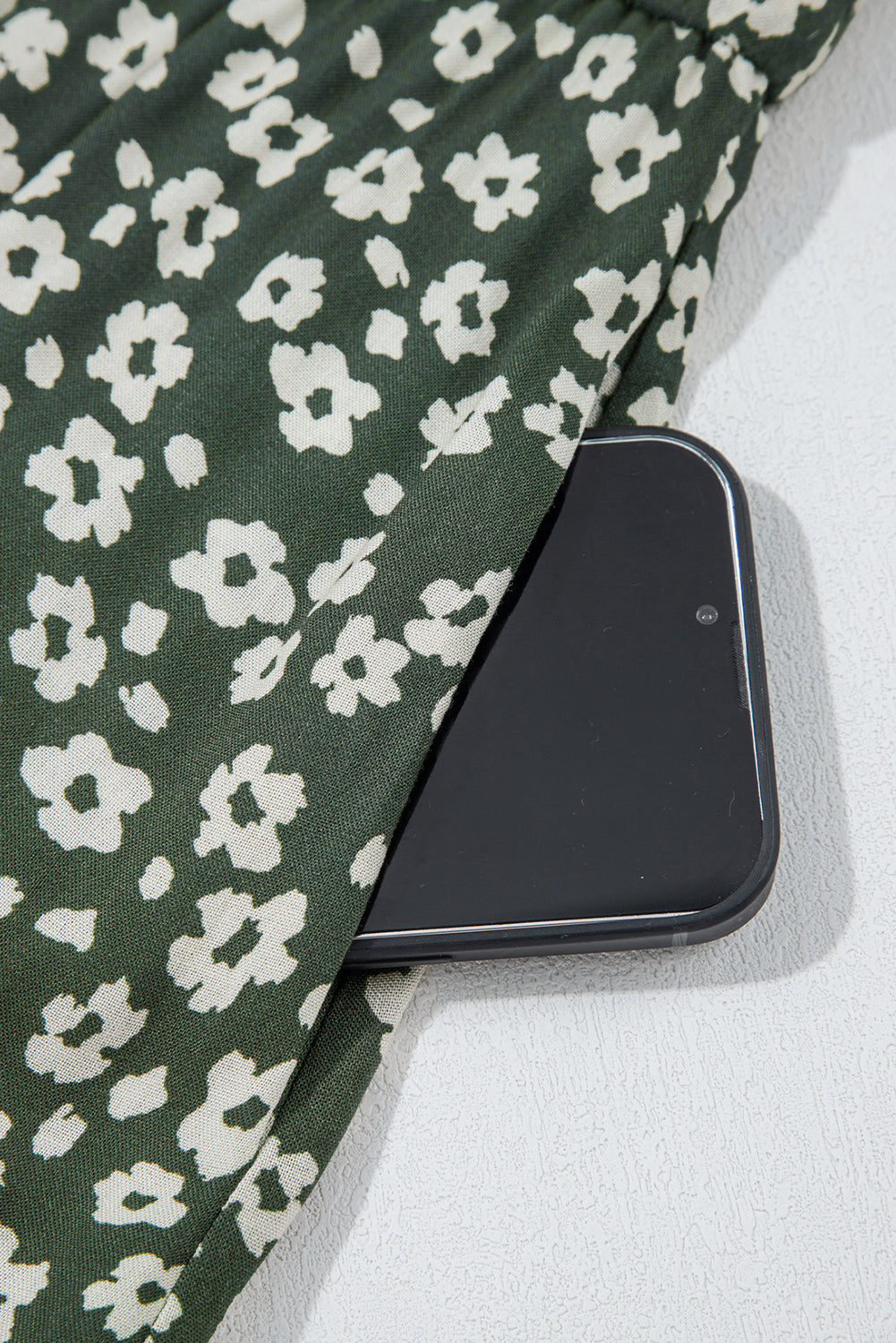 Green floral dress with white flower print, phone in pocket, close-up detail