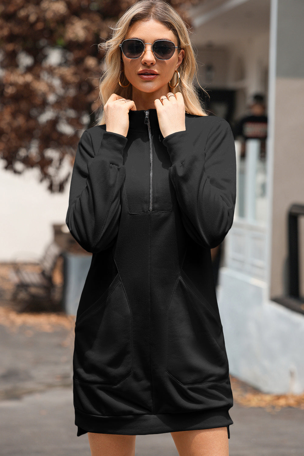 Woman outdoors wearing black long sleeve zip-up sweatshirt dress with pockets and sunglasses