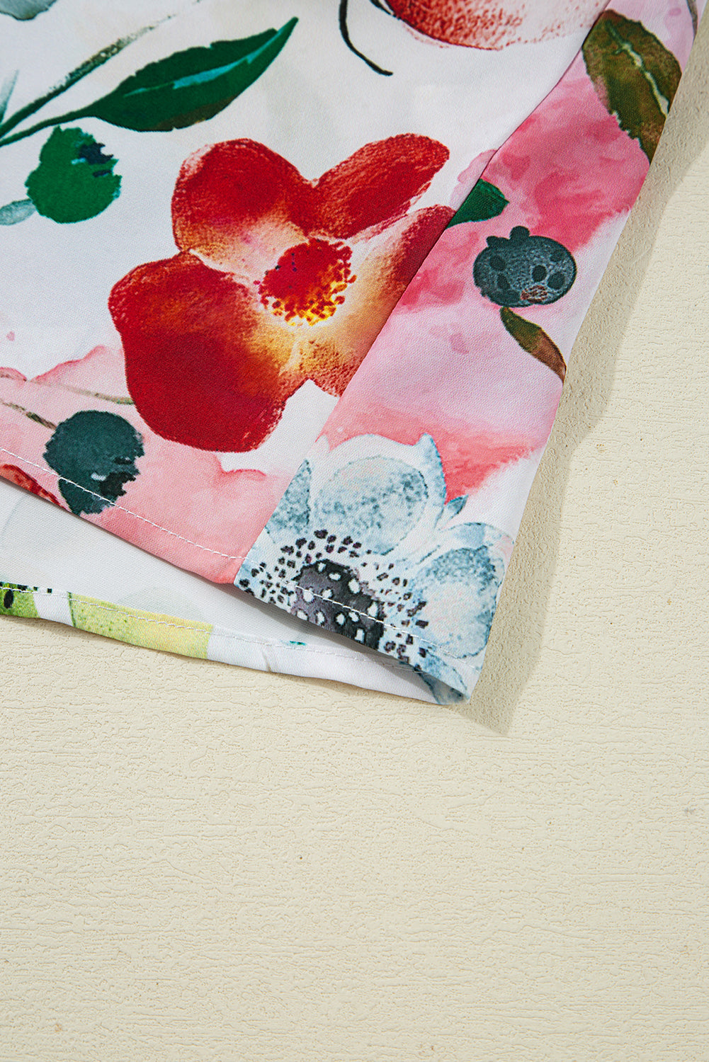 Close-up of floral print fabric with vibrant red and blue flowers and green leaves.