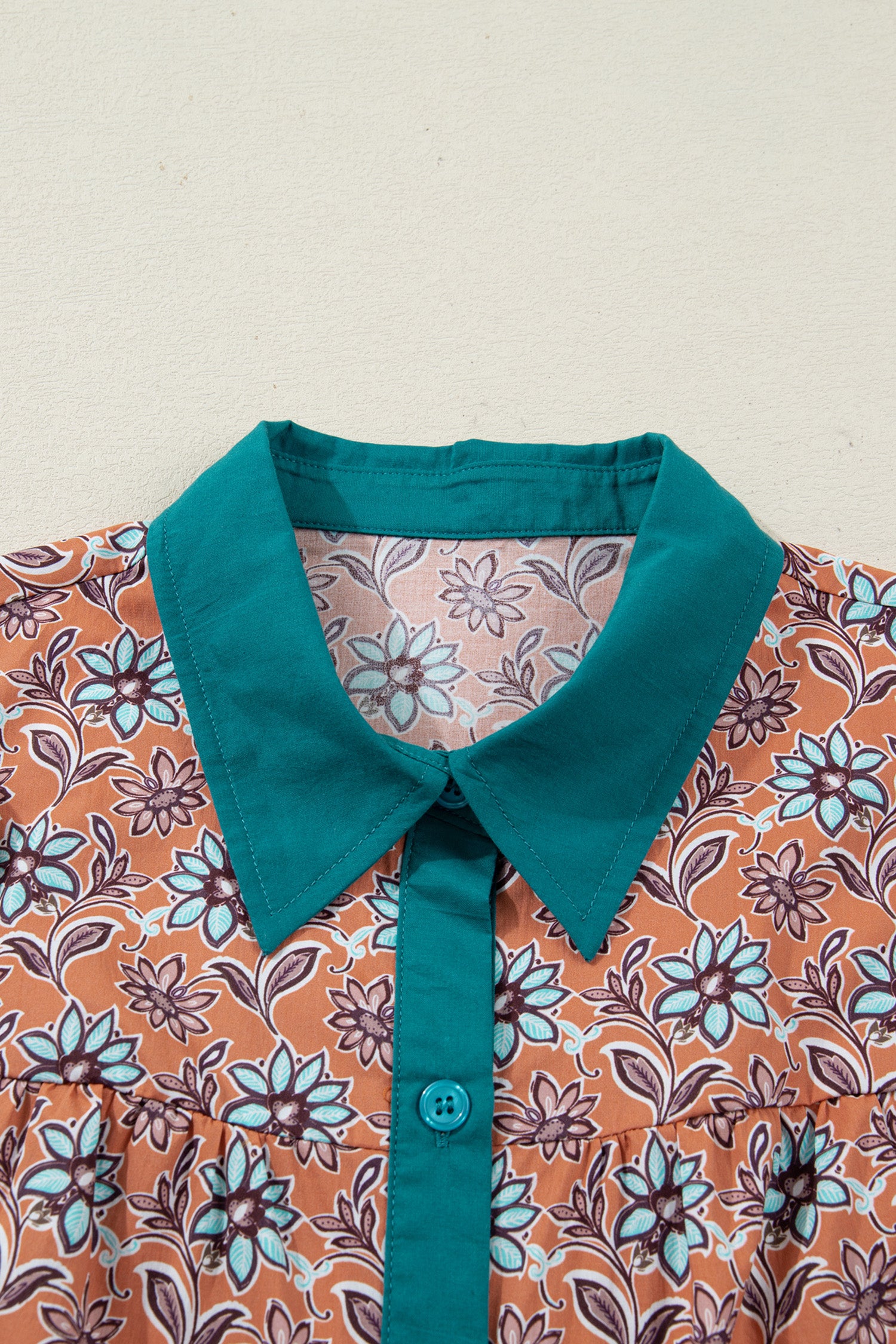 Close-up of floral print shirt with teal collar and button placket