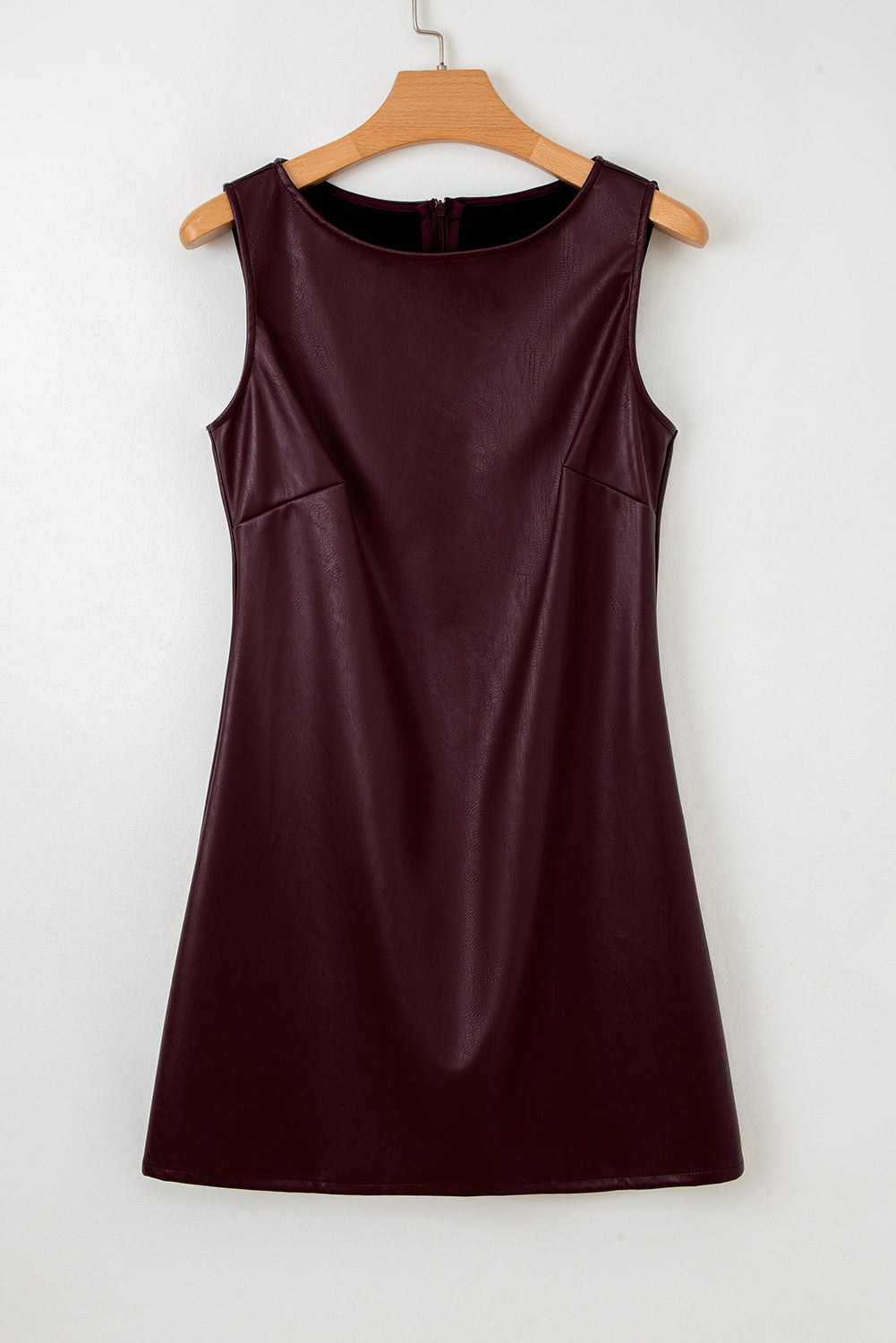 Sleeveless dark burgundy faux leather dress with round neckline on wooden hanger