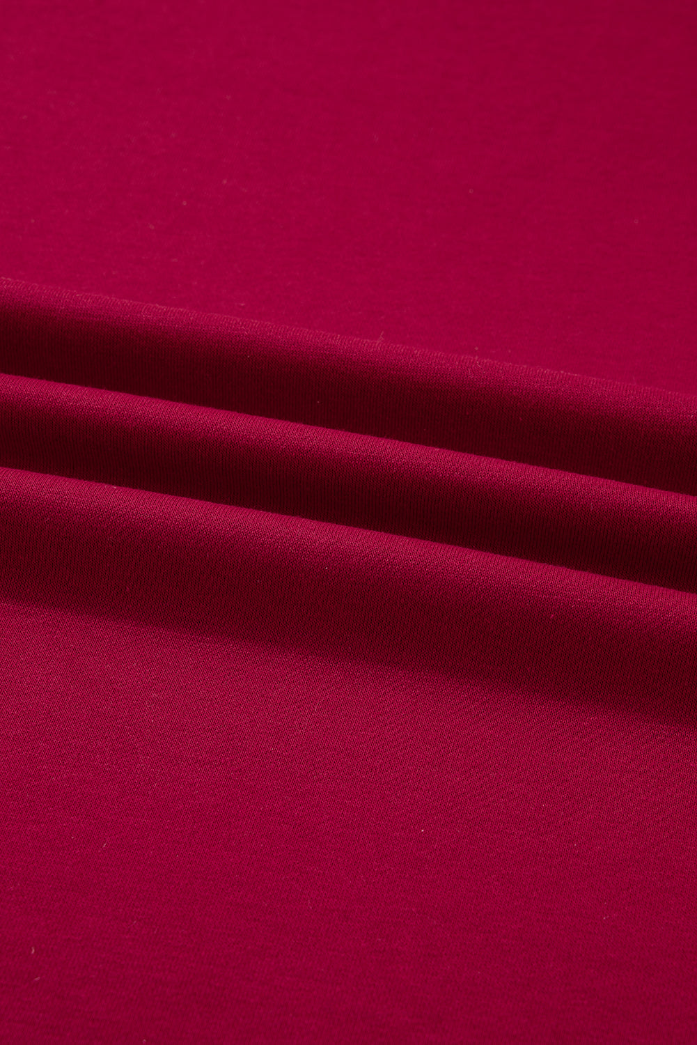 Close-up of burgundy red cotton fabric with soft folds, textile texture