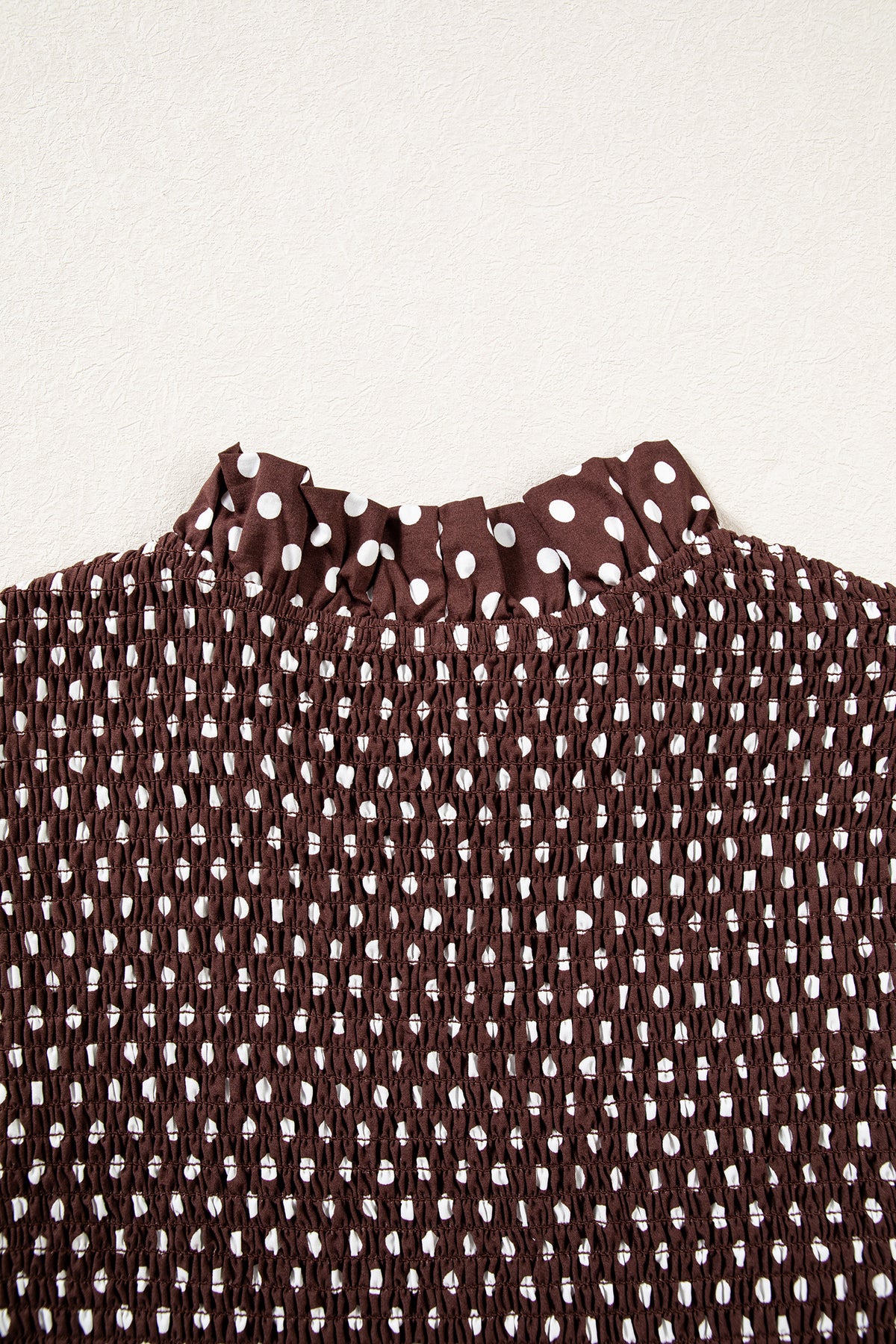 Кафяво блуза с бели точки и набрана еластична горна част, показана в близък план отгоре