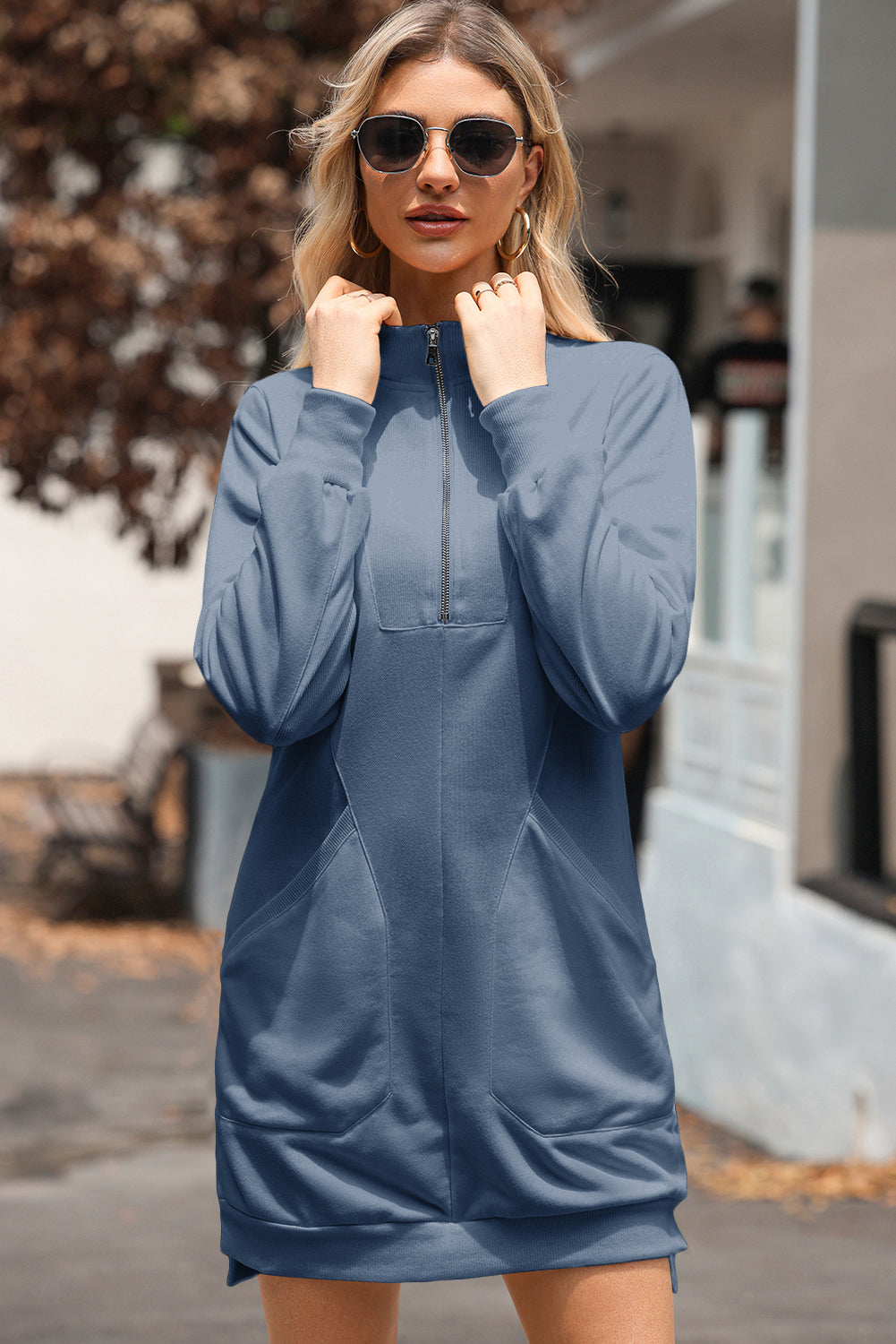 Woman wearing blue casual zip-up sweatshirt dress, sunglasses, outdoors