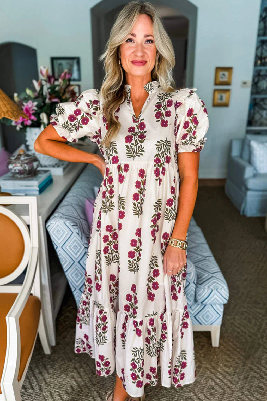 Woman wearing a white floral midi dress with puffed sleeves, standing in a stylish living room.