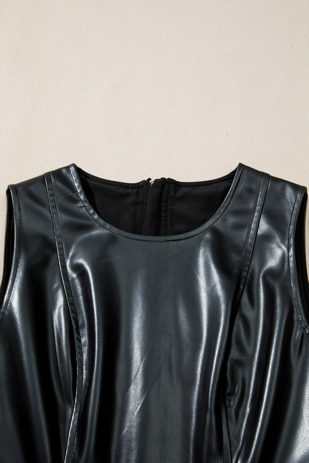 Close-up of sleeveless black faux leather dress with round neckline and back zipper
