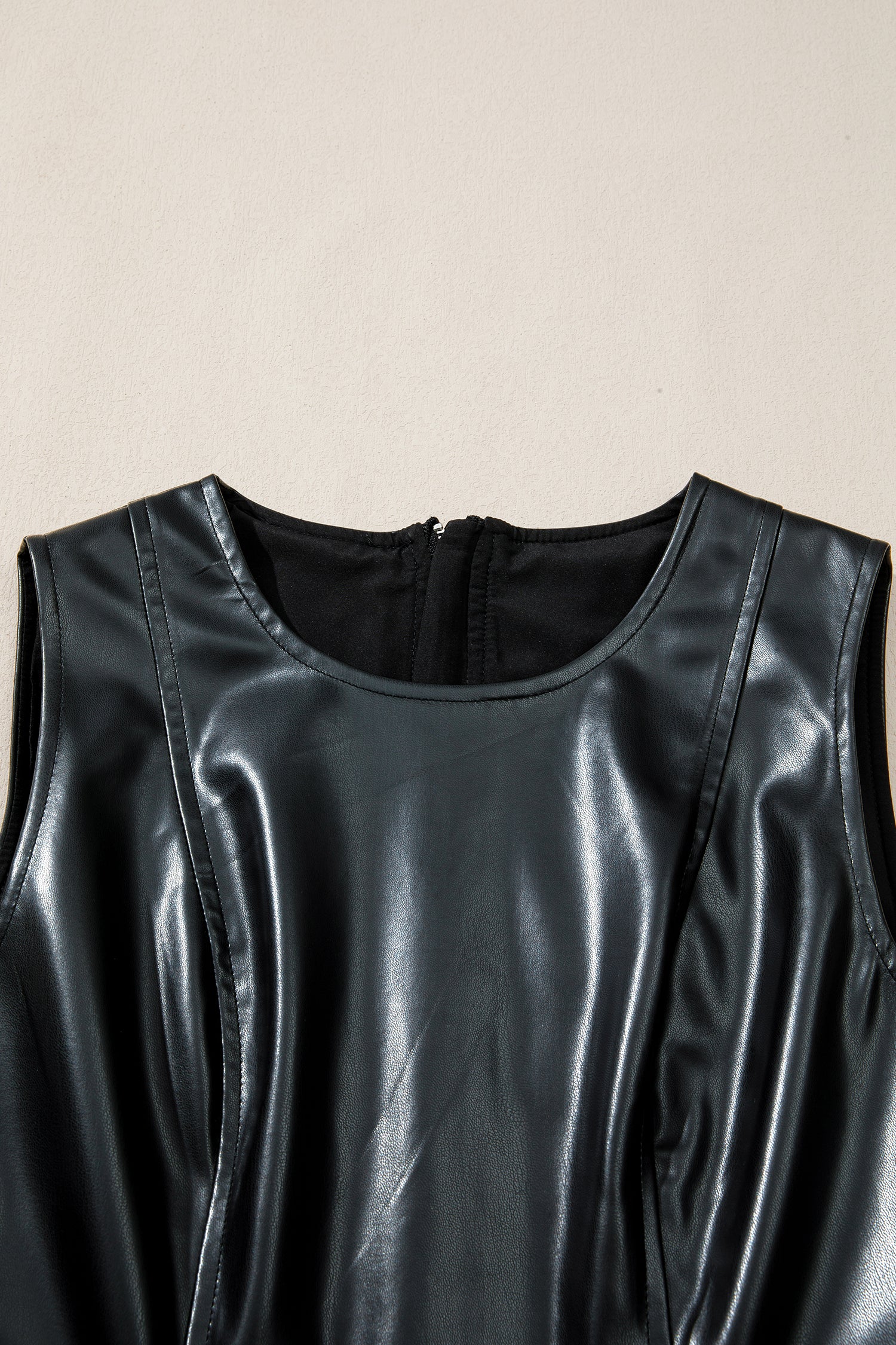 Close-up of sleeveless black faux leather dress with round neckline and back zipper