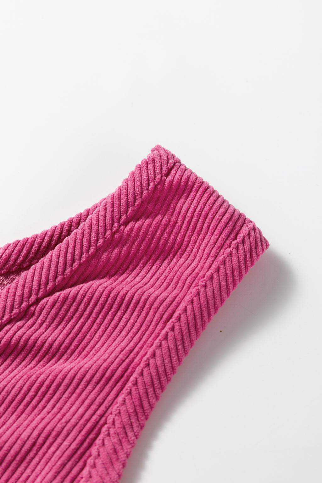 Close-up of pink ribbed knit fabric, textured textile on a white background
