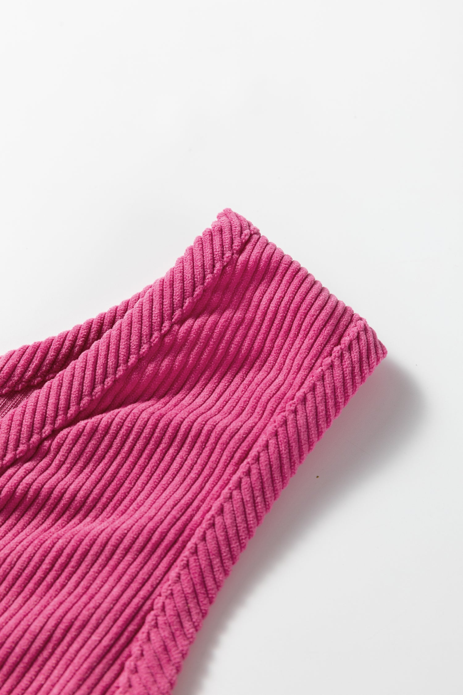 Close-up of pink ribbed knit fabric, textured textile on a white background