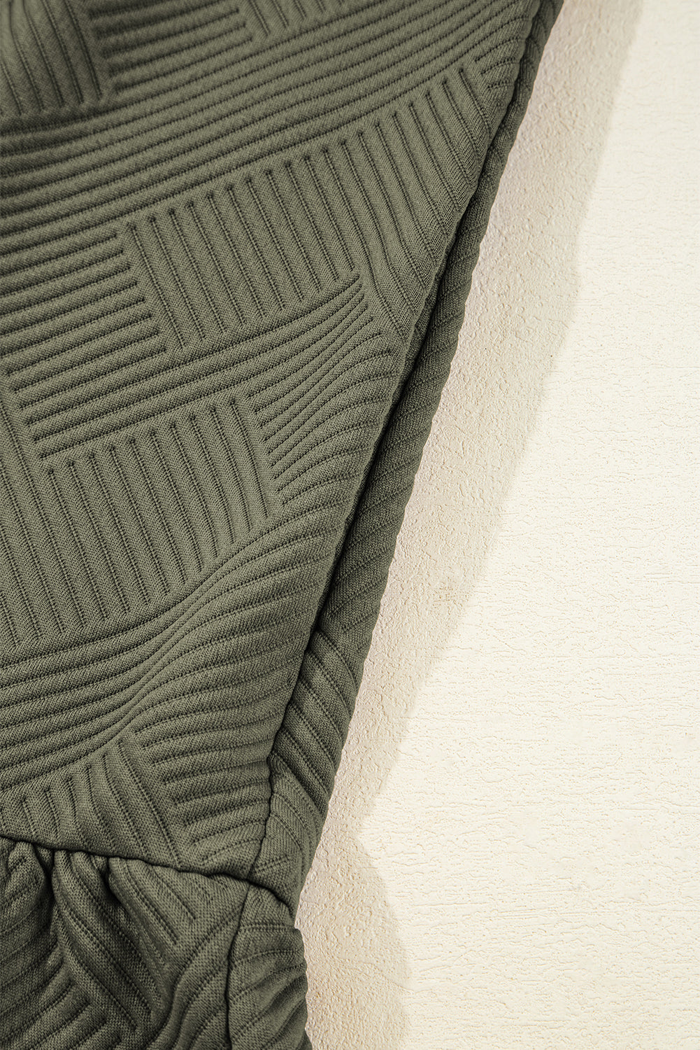 Close-up of textured olive green ribbed fabric on a garment sleeve