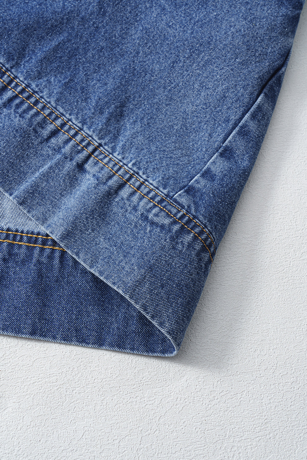 Close-up of blue denim jeans hem with visible yellow stitching on textured white surface