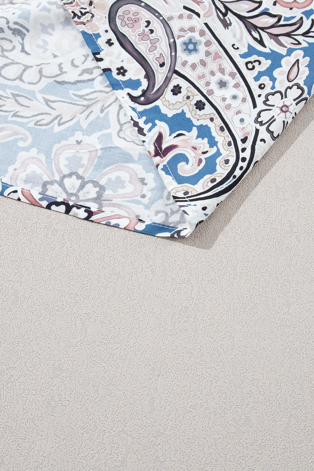 Close-up of blue and white paisley patterned fabric on a light textured surface