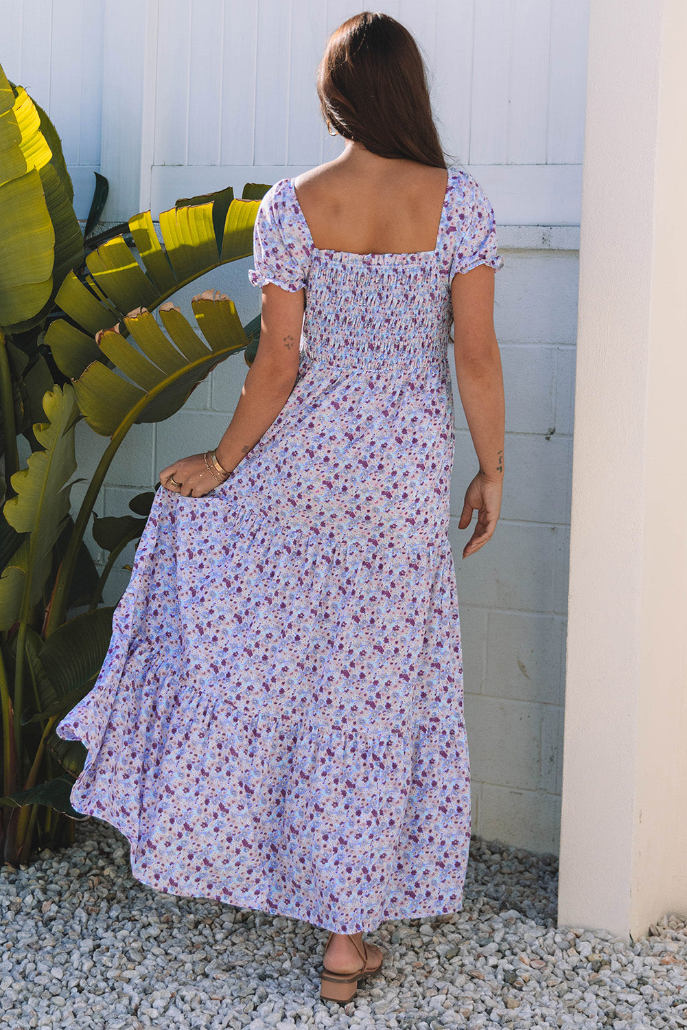 Woman in a flowy floral maxi dress with short sleeves standing outdoors on gravel