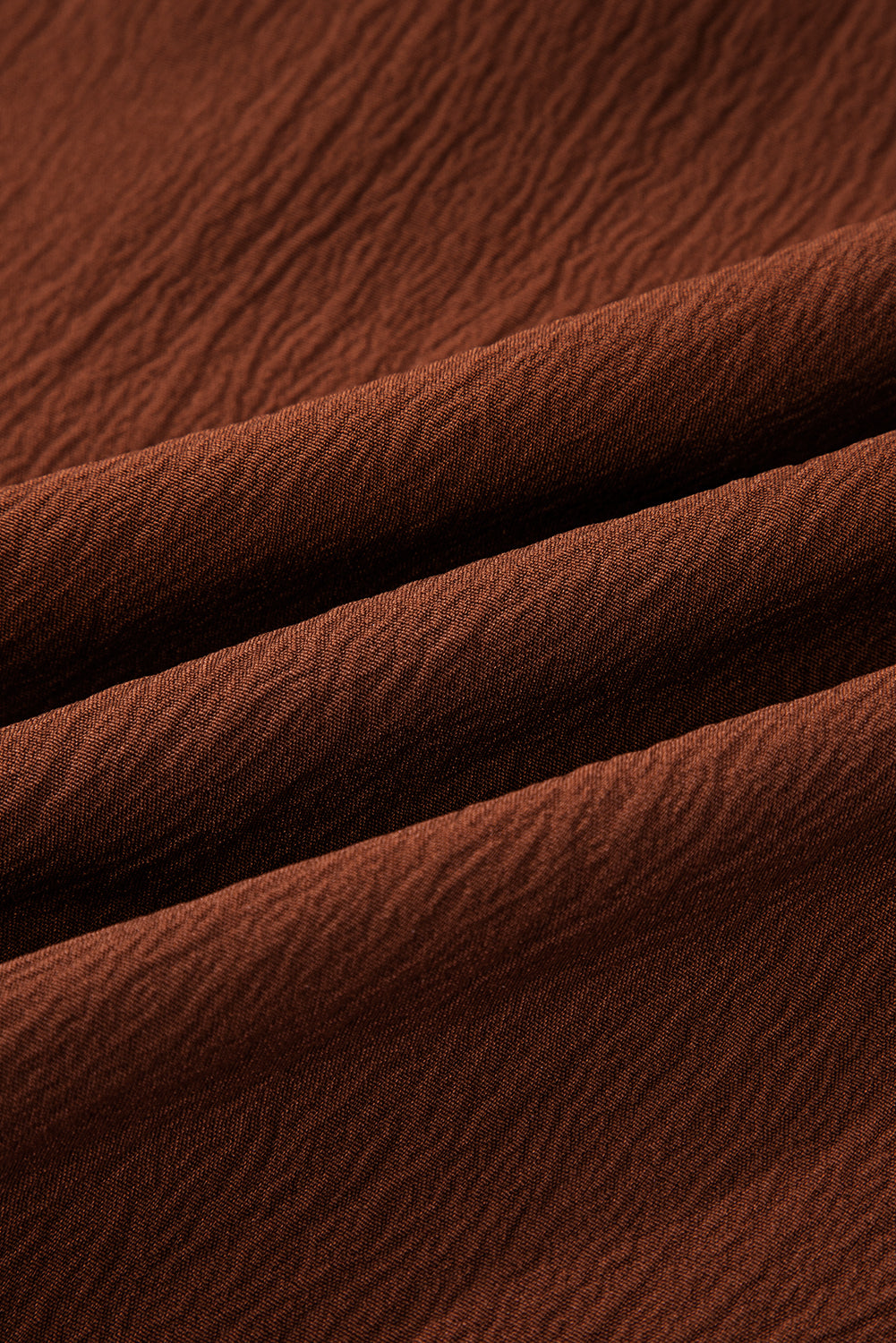 Close-up of textured brown fabric with soft folds and visible weave pattern