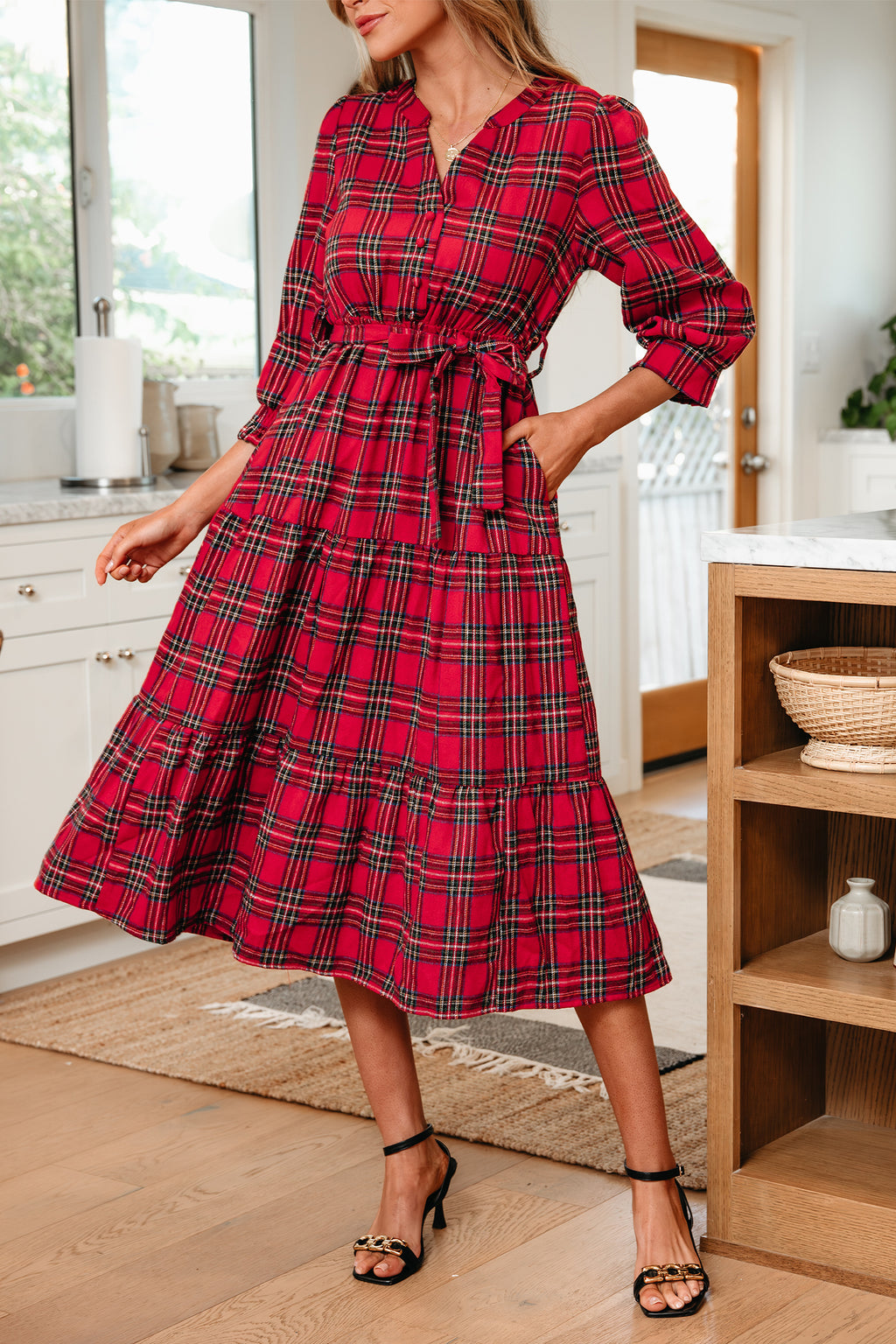 Woman wearing a red plaid midi dress with waist tie in a modern kitchen setting