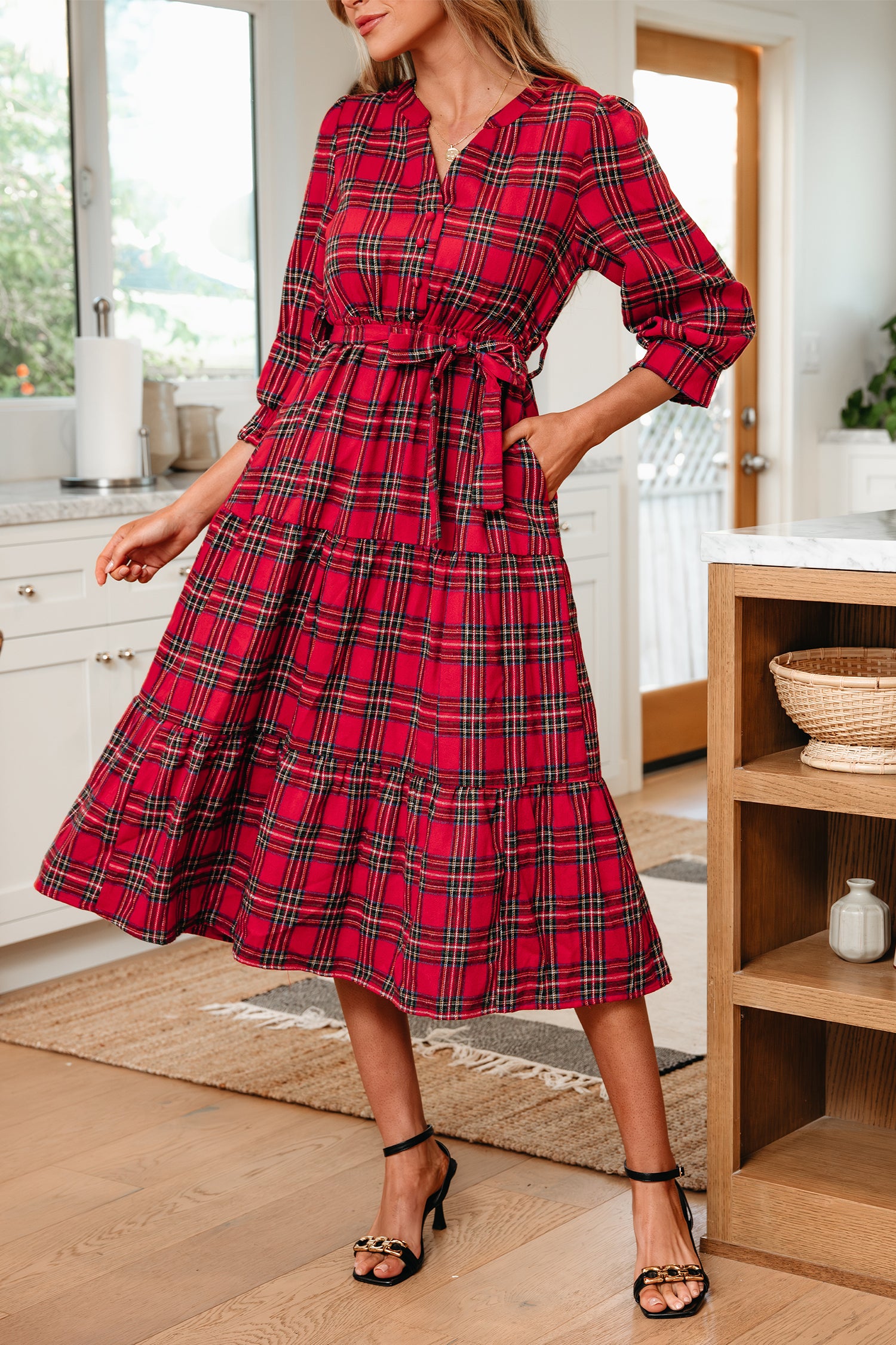 Woman wearing a red plaid midi dress with waist tie in a modern kitchen setting