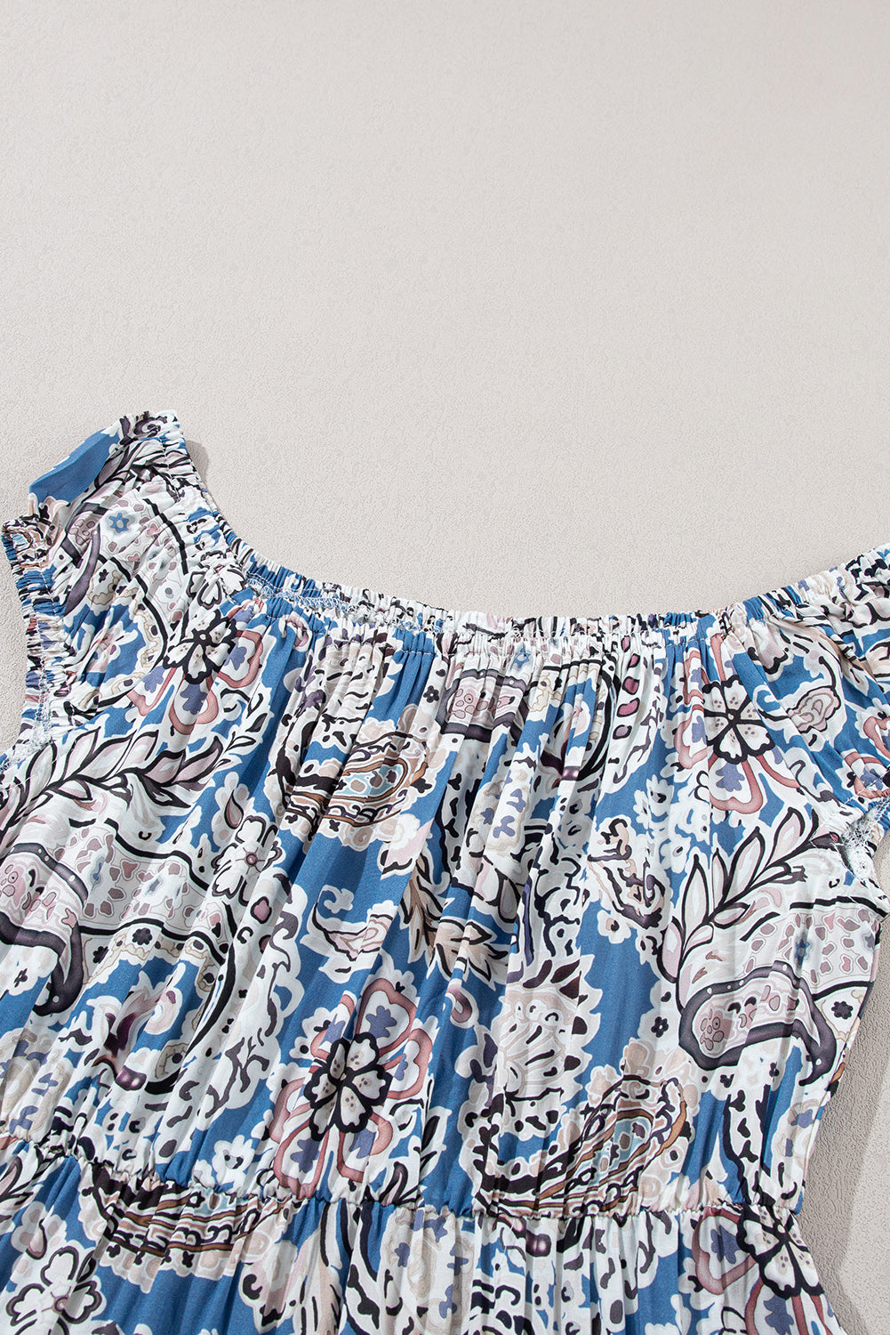 Blue and white floral boho dress with smocked neckline and ruffle sleeves, laid flat