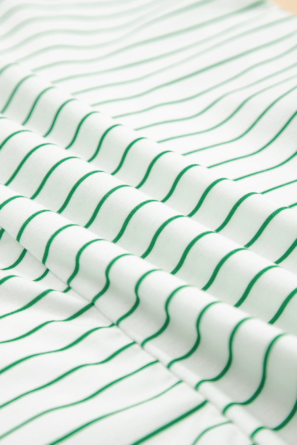 Close-up of white fabric with green vertical stripes, soft textured textile pattern