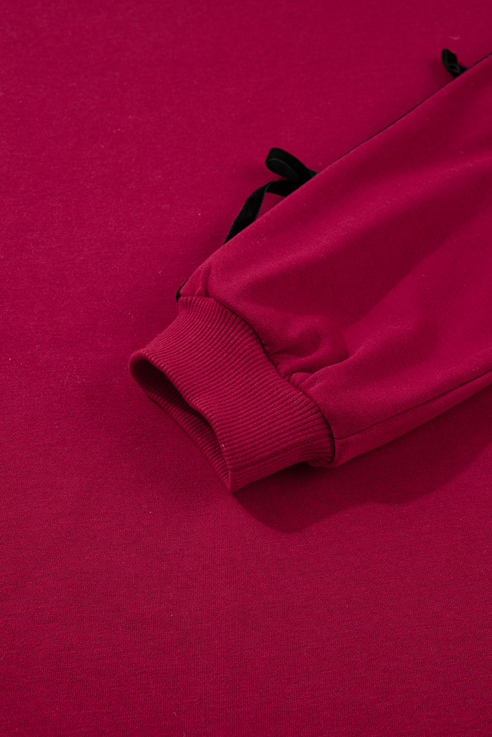 Close-up of a red sweatshirt sleeve with ribbed cuff, casual loungewear fabric
