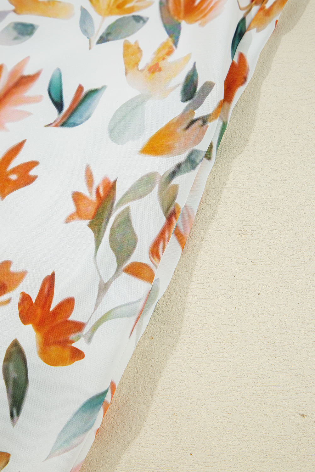 White fabric with orange and green abstract floral print, close-up detail