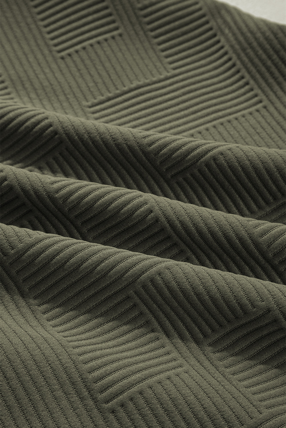 Close-up of olive green ribbed textured fabric with geometric pattern