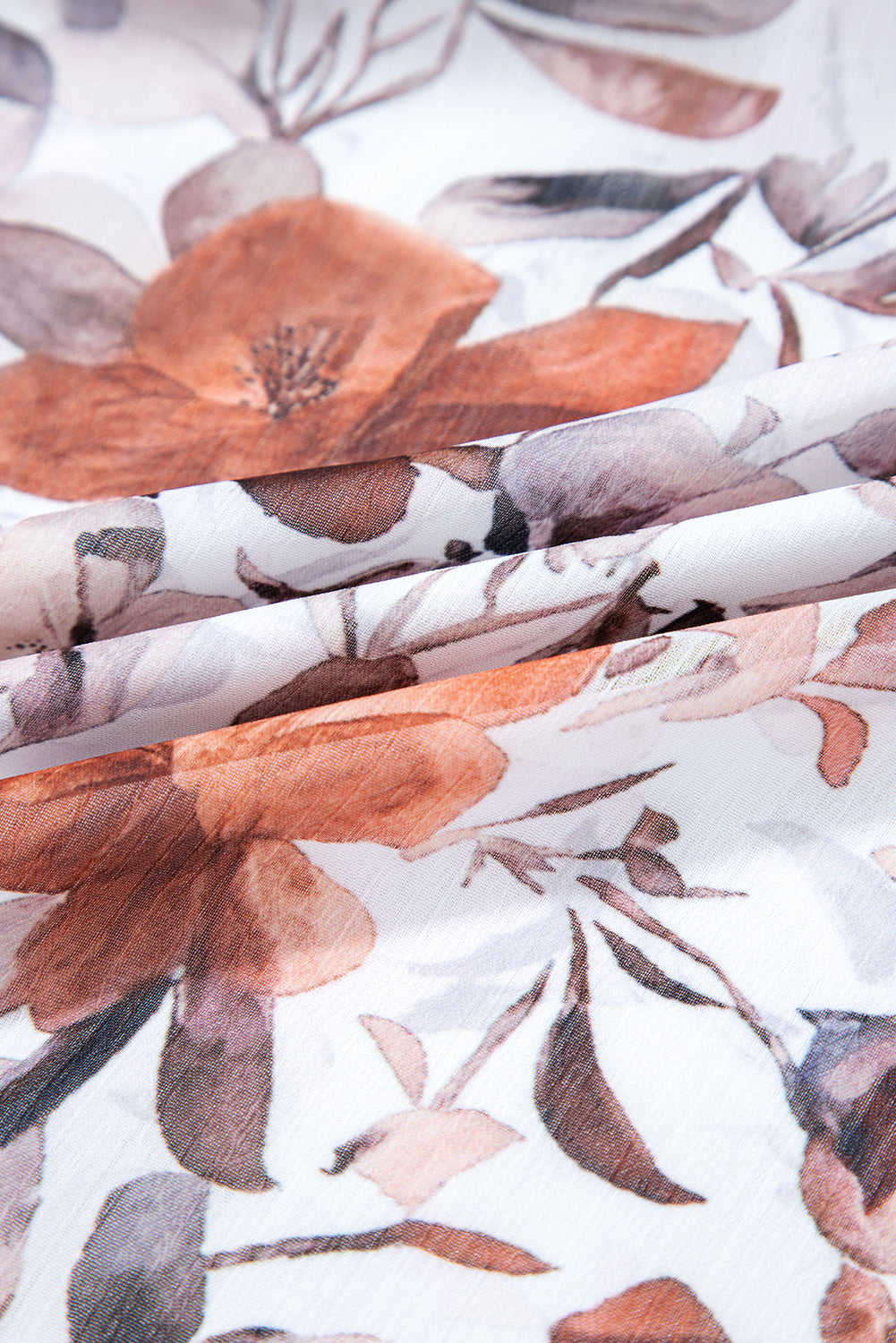 White fabric with brown and beige floral print and soft texture, close-up view