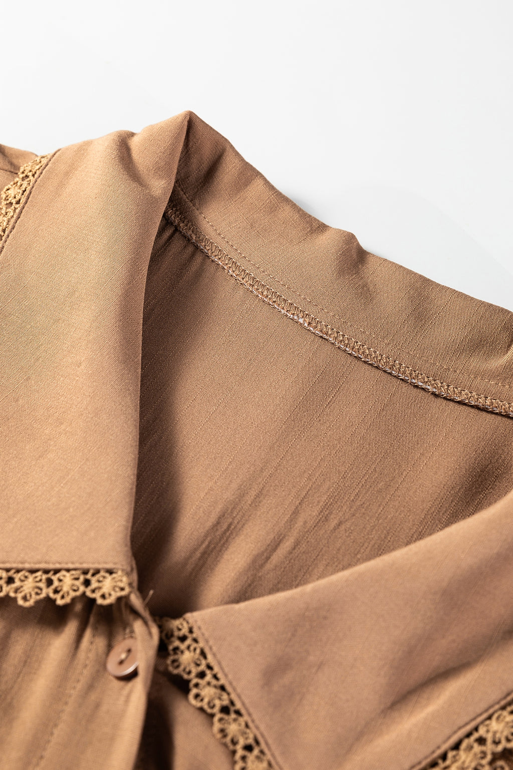 Close up of light brown blouse collar with delicate lace trim and button detail