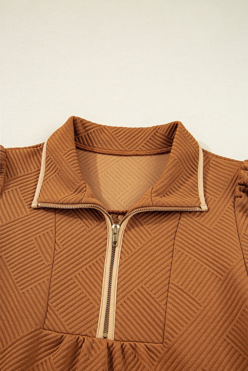 Brown textured zip-up jacket with a geometric pattern and stand collar on a light background