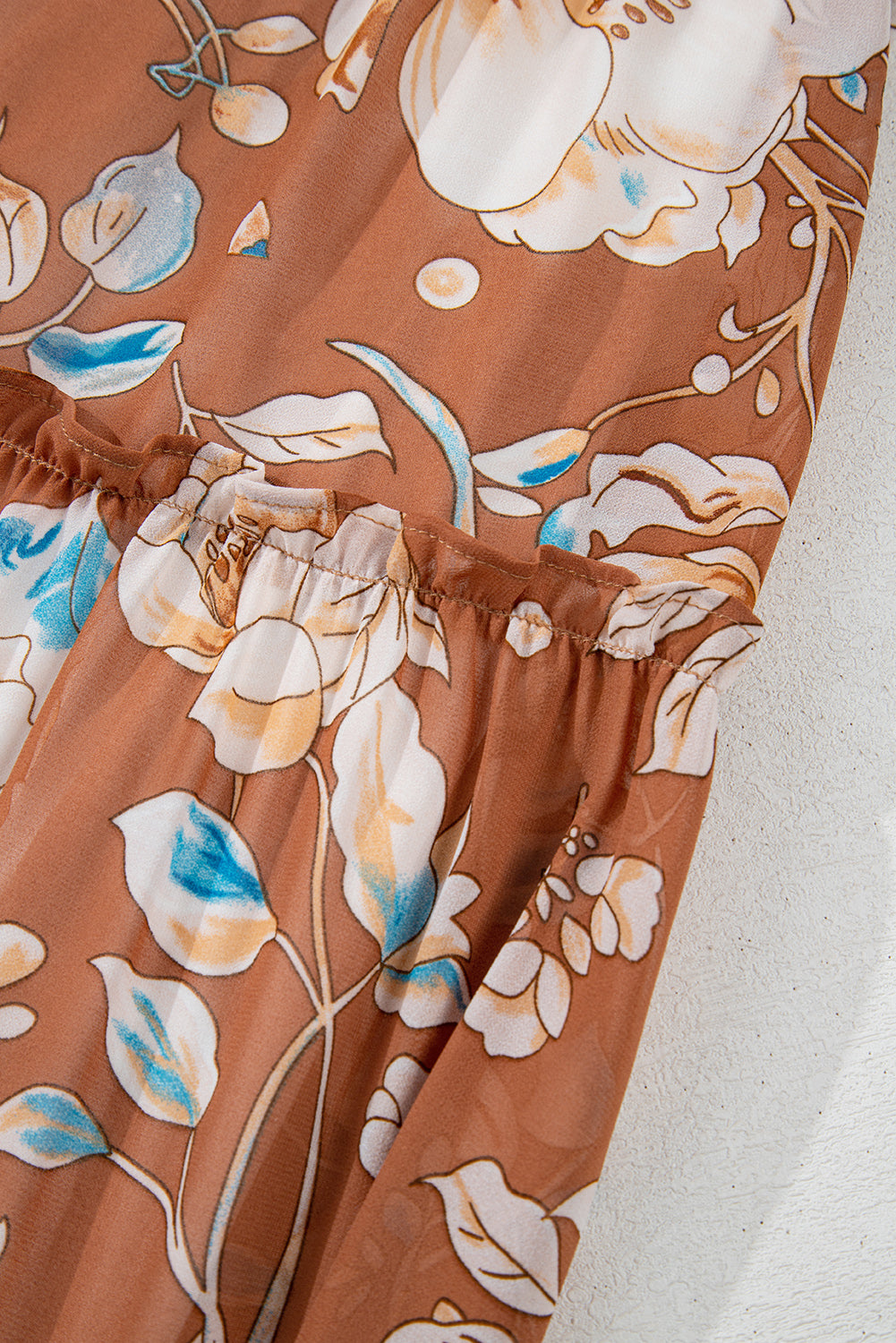 Close-up of brown floral chiffon dress with white and blue flowers and gathered waist detail