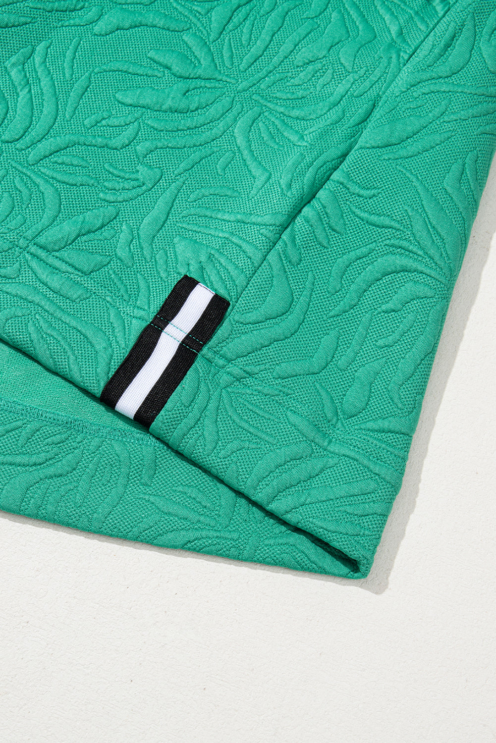 Green textured fabric with leaf pattern and black-white stripe detail