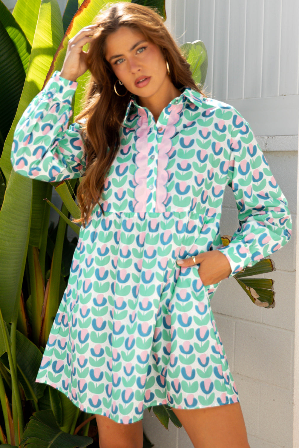 Woman wearing a long sleeve mini dress with colorful geometric tulip print, standing outdoors.