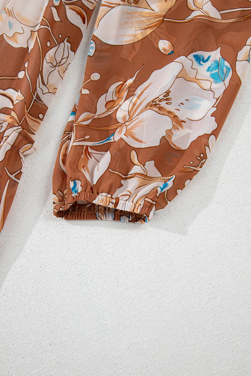 Brown floral print sleeve with elastic cuff on textured white background