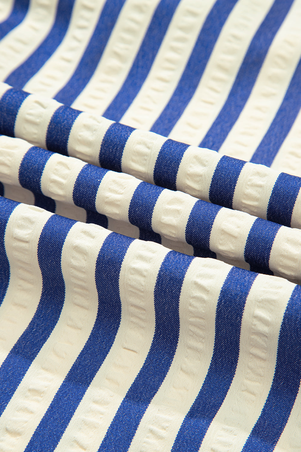 Blue and white striped textured fabric with raised detailing, close-up view