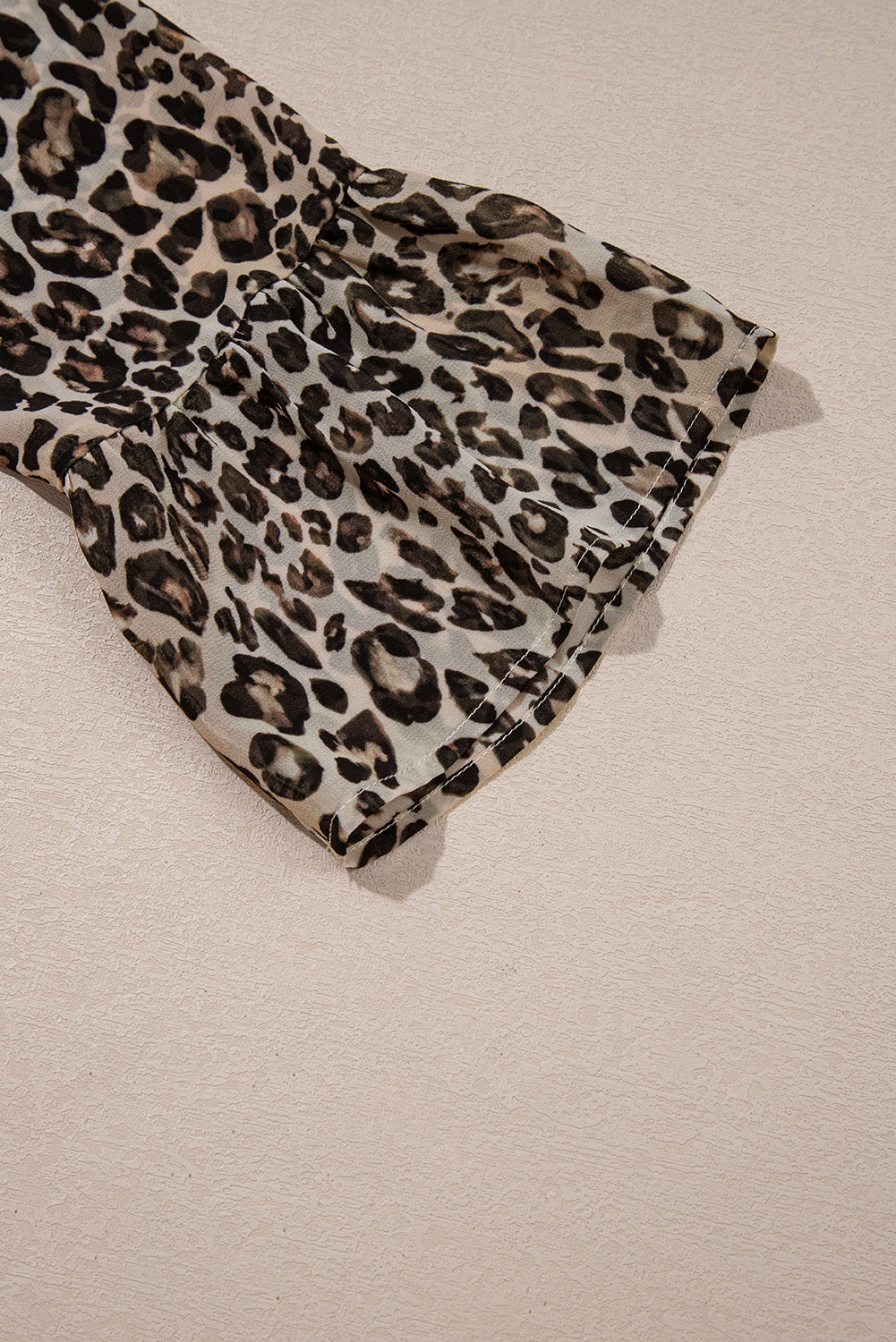 Leopard print chiffon sleeve detail on beige background