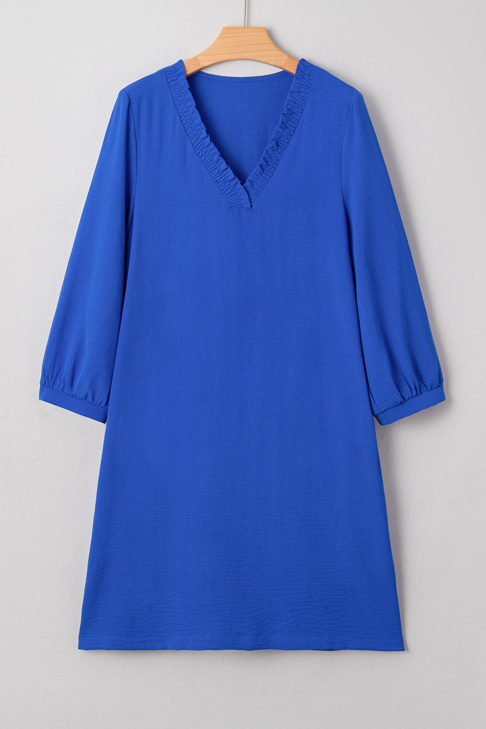 Royal blue dress with V-neck and three-quarter sleeves on wooden hanger