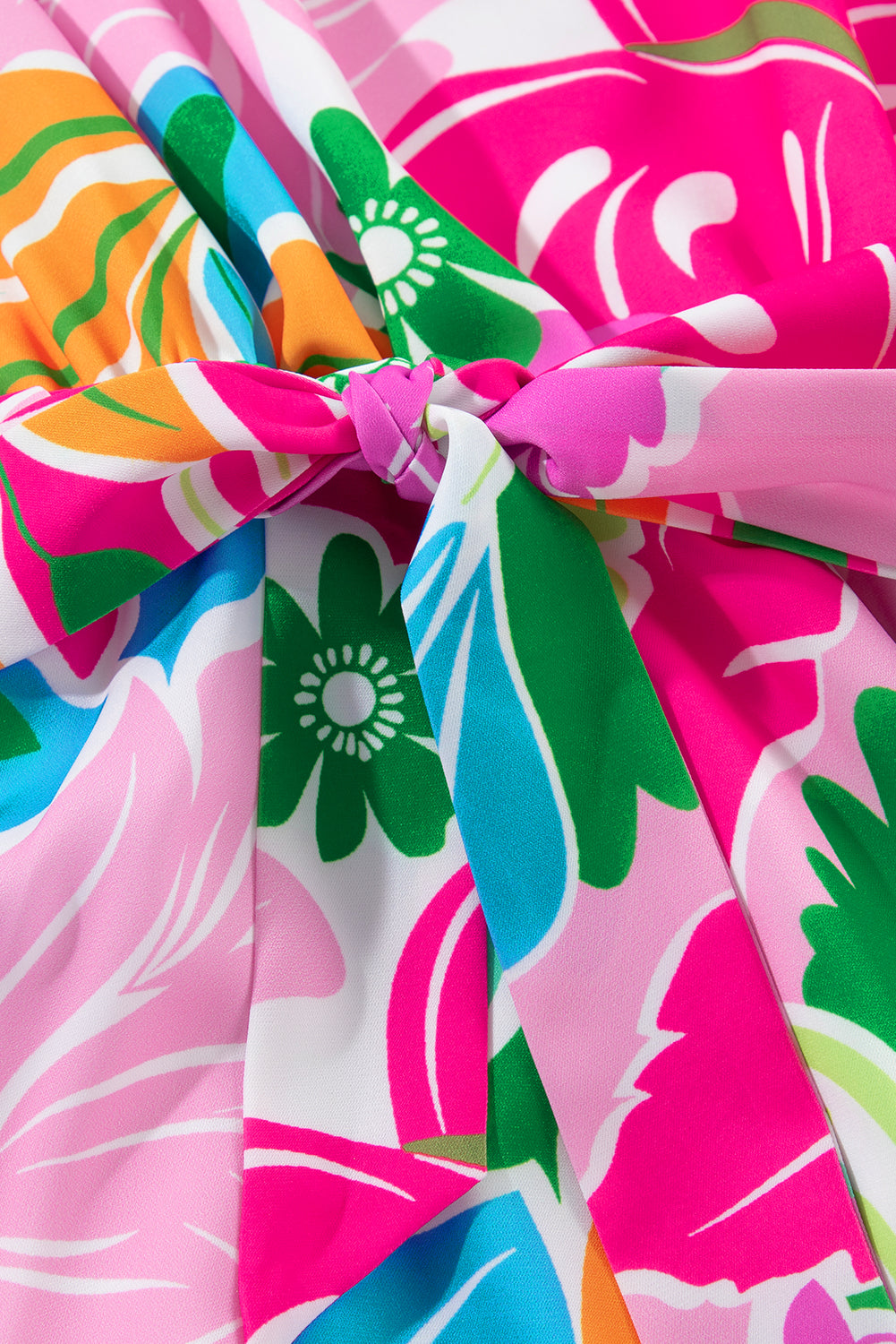 Colorful floral fabric with pink, green, blue, and orange pattern, tied in a stylish knot