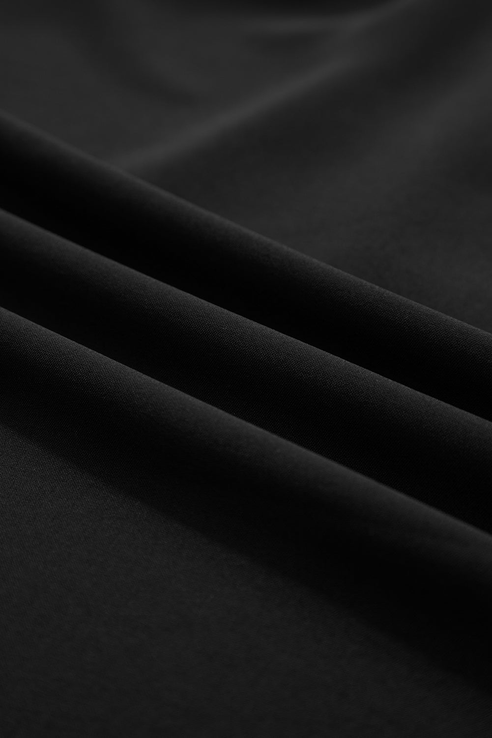 Close-up of smooth black fabric with soft folds, textile texture detail