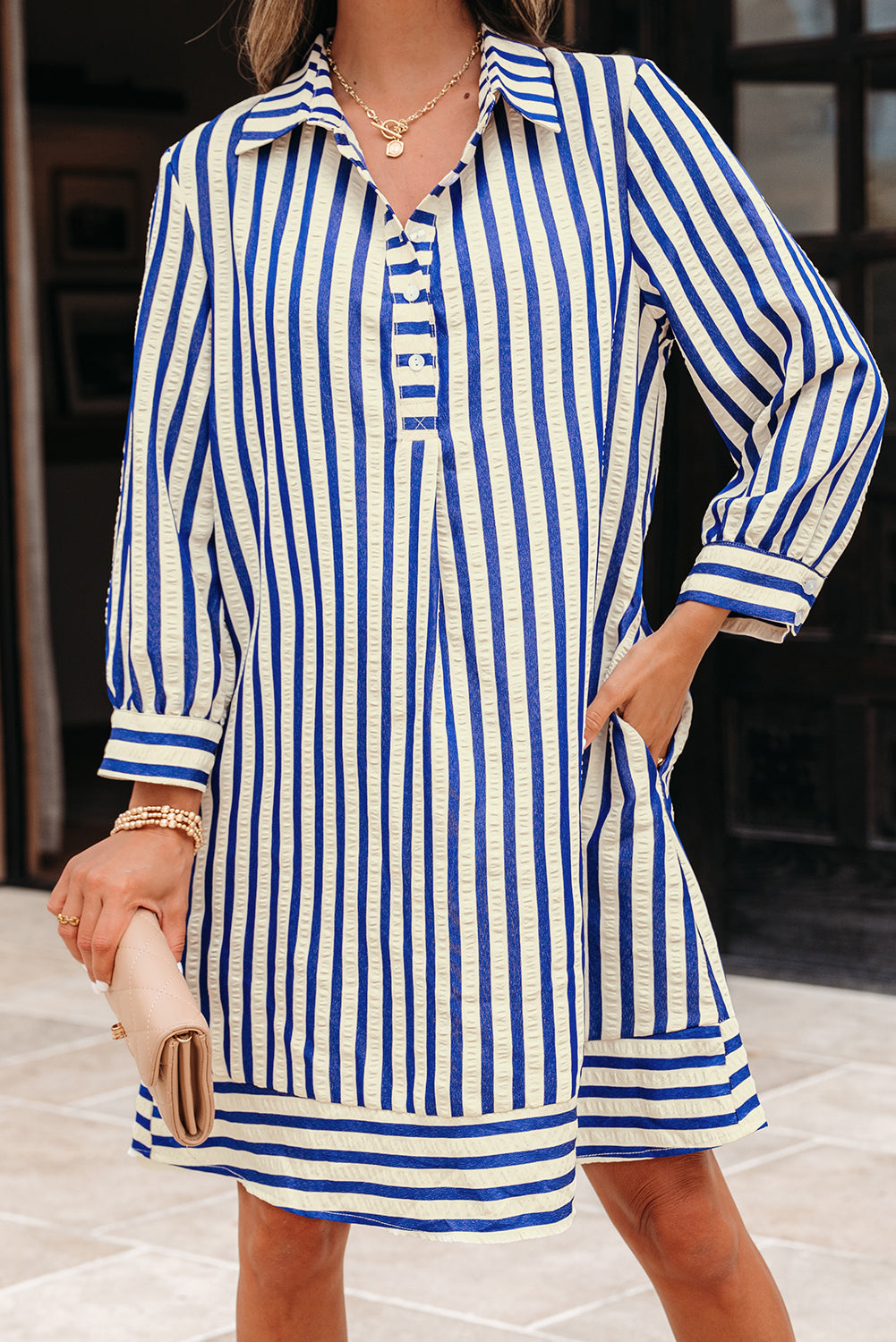 Woman wearing a blue and white striped shirt dress with long sleeves and pockets