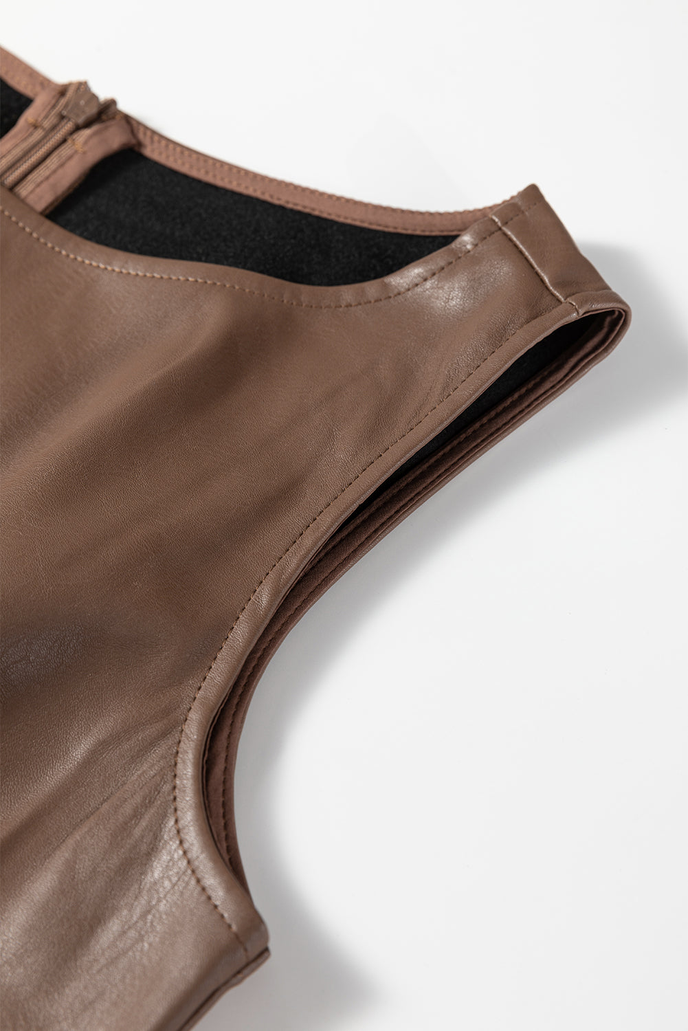 Close-up of brown faux leather sleeveless top with zipper and stitch detailing