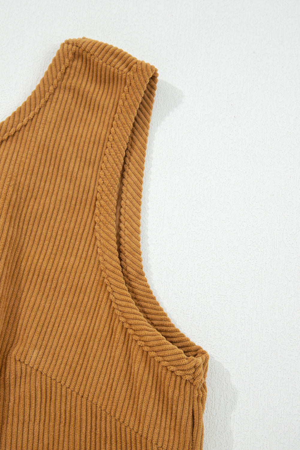 Close-up of ribbed brown knit tank top with sleeveless design on light background