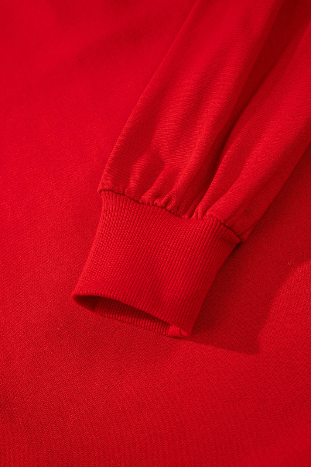 Close-up of red sweatshirt sleeve with ribbed cuff, soft cotton fabric